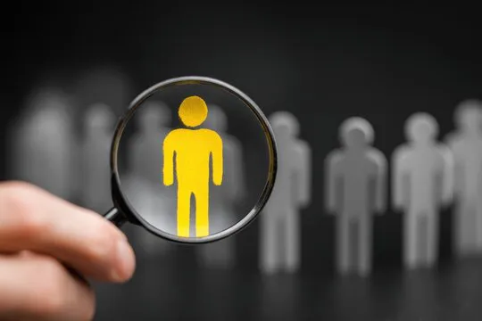 Hand holding magnifying glass focusing on a person