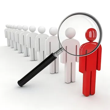 A line of generic white human figures, with one figure at the front of the line highlighted in red. A magnifying glass is positioned over this red figure, drawing attention to it.