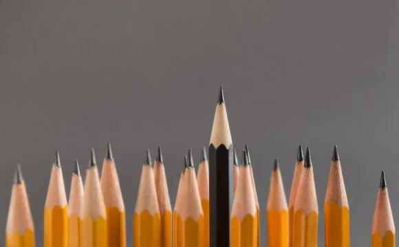 Row of nails hammered into wooden plank, one golden is higher