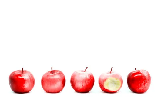 Bitten apple among whole ones on white background.