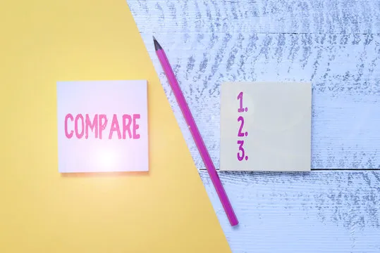 Conceptual hand writing showing Compare. Concept meaning Estimate Measure Note the similarities dissimilarities between Blank notepads pen colored paper sheet wooden background