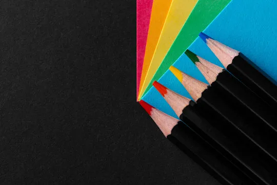 Colored rainbow paper corners and Black wooden colored pencil set on black textured background. Business concept. Layout for design. Copy space. High quality photo