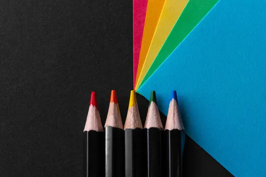 Colored rainbow paper corners and Black wooden colored pencil set on black textured background. Business concept. Layout for design. Copy space. High quality photo