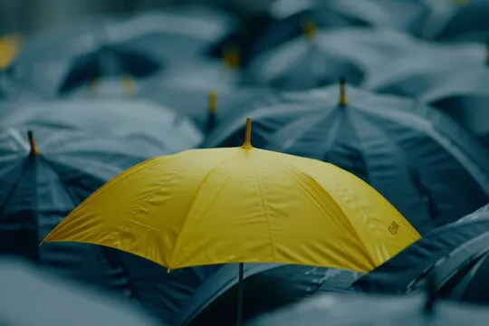 An umbrella with a unique yellow color, standing out in a crowd of gray, illustrating individuality and difference.